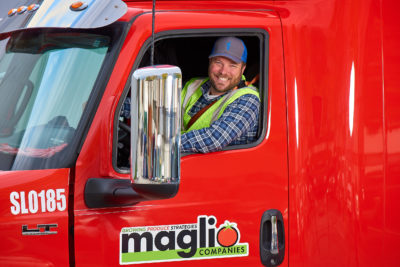Truck driver smiling from red Maglio truck cab window