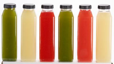 Six multi-colored bottles of cold-pressed juice with black caps