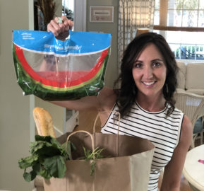 Smiling woman in striped shirt holding a Maglio ReadyRipe watermelon bag