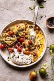 Bowl of pasta with tomatoes and cheese and fork on slate background